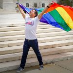 un uomo che sventola una bandiera arcobaleno simbolo della comunità LGBT+