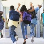 Ragazze e ragazzi in età scolare corrono per un corridoio di scuola