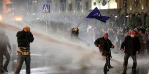 Una donna georgiana sventola una bandiera dell'Unione Europea contro gli idranti della polizia che tenta di reprimere la protesta