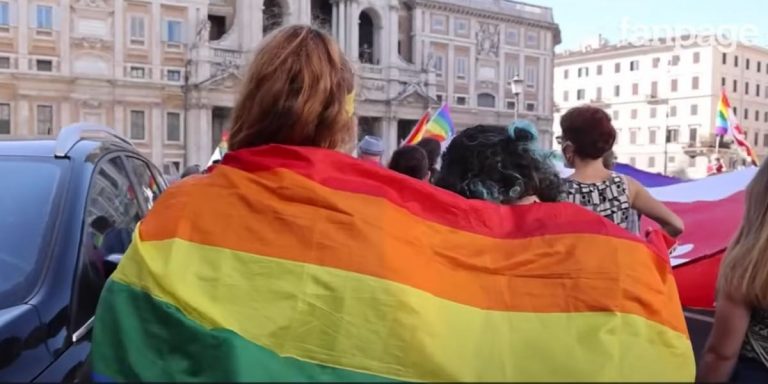 Due donne camminano avvolte in una bandiera arcobaleno durante il Roma Pride