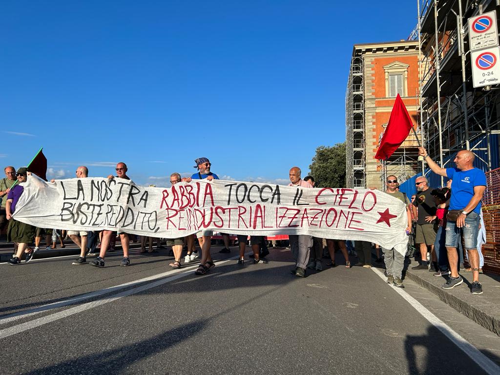 Manifestanti dell'ex Gkn con uno striscione con su scritto "La nostra rabbia tocca il cielo. Buste, reddito, reindustrializzazione".