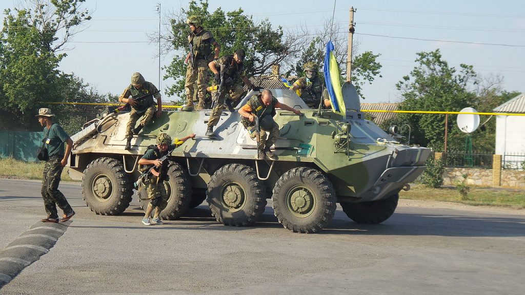 Soldati scendono da un carro armato con bandiere ucraine in Donbas.