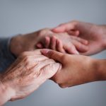 Le mani di un caregiver stringono quelle di una persona anziana. L'Alzheimer è una malattia devastante che colpisce non solo i malati, ma anche le loro famiglie e i caregiver. È fondamentale investire nella ricerca, nell'assistenza e nella sensibilizzazione per affrontare questa sfida collettivamente.