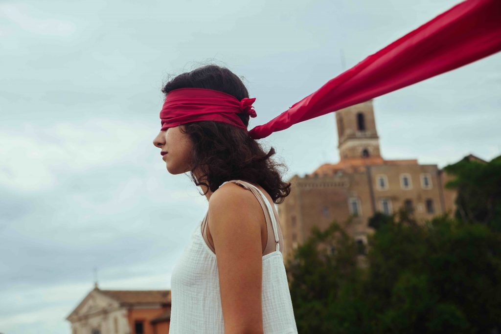 Una donna con una benda rossa agli occhi protesta durante le manifestazioni a un anno dalla morte di Jina Mahsa Amini. Nonostante le proteste siano meno frequenti e abbiano perso l'intensità dell'inizio, l’anniversario della morte di Jina Mahsa Amini è stato celebrato con iniziative e manifestazioni di solidarietà in diverse città in tutto il mondo. Abbiamo raccolto le voci della diaspora iraniana in Italia.