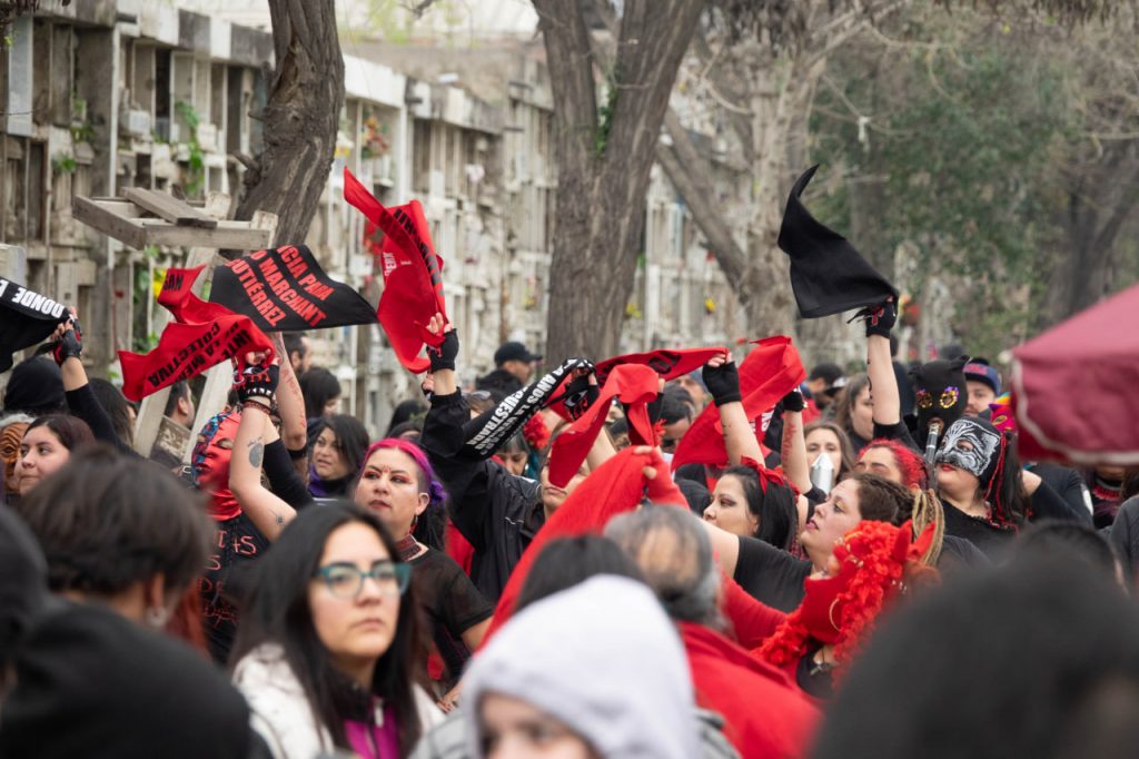 Tante donne sfilano per Santiago del Cile vestite di nero con fazzoletti rossi.