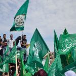una folla di persona che sventola bandiere di Hamas