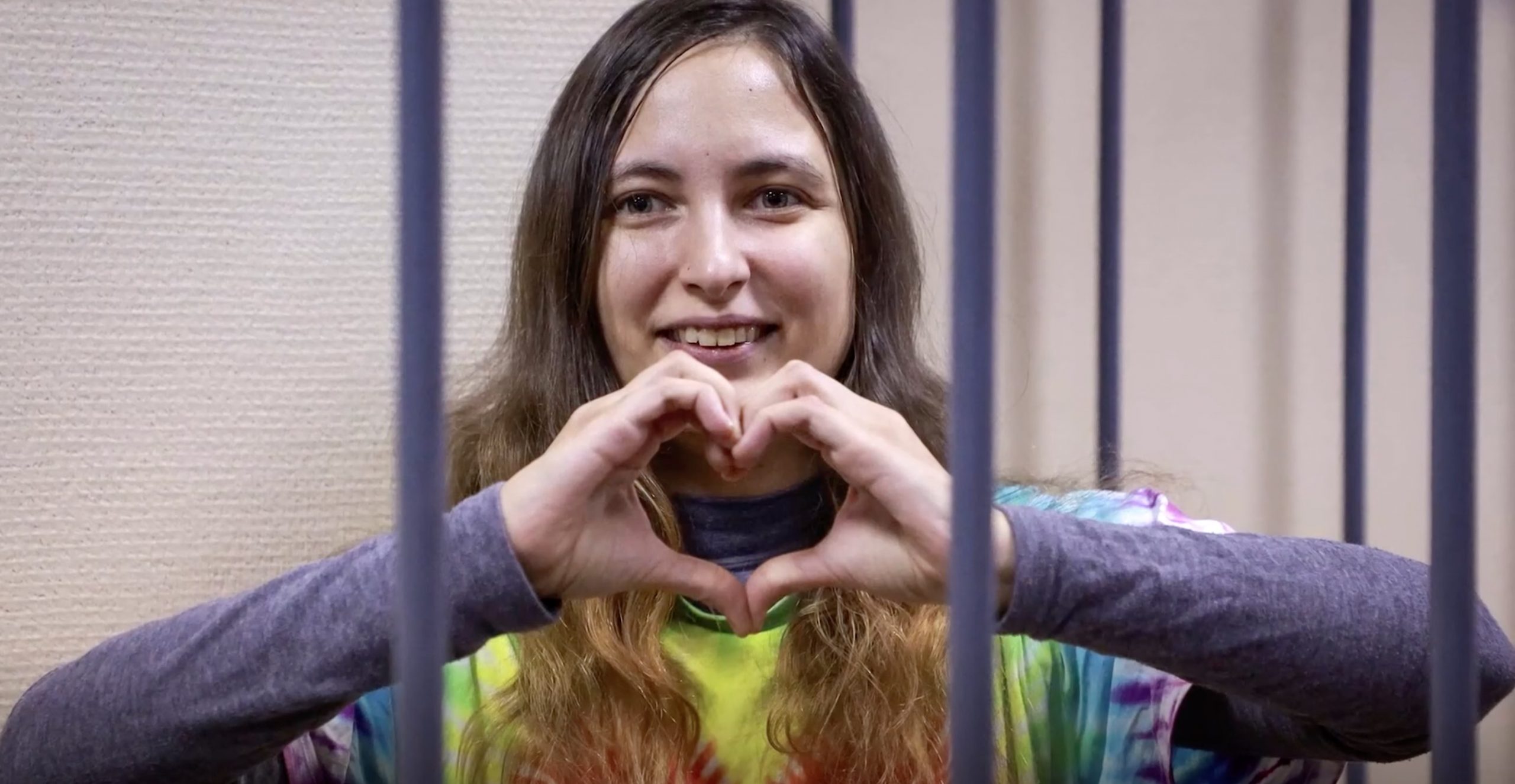 L'attivista russa Saša Skočilenko unisce le mani a forma di cuore dietro le sbarre nel processo che l'ha vista condannata a 7 anni di colonia penale.