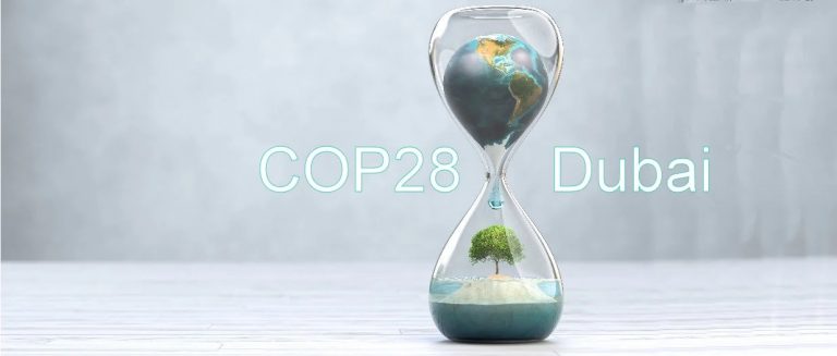 Una clessidra con il mondo che scorre come il tempo e sullo sfondo la scritta "COP28 Dubai"