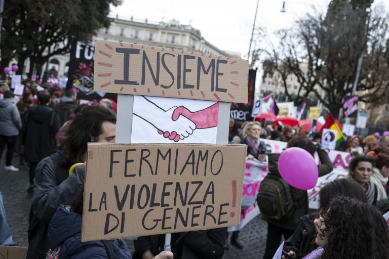 Un cartello tenuto da un uomo durante una manifestazione contro la violenza di genere con su scritto "Insieme fermiamo la violenza di genere"