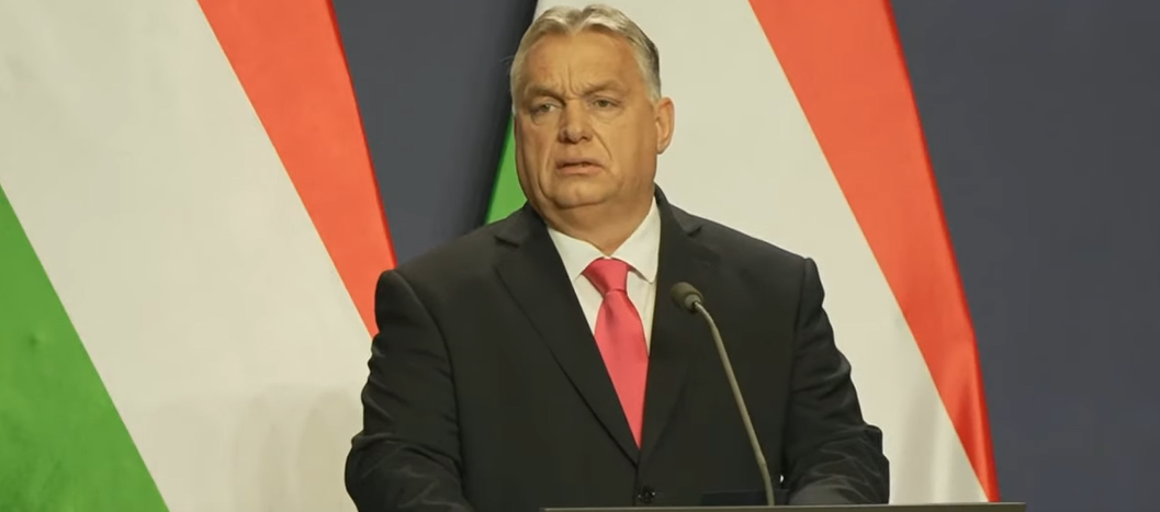 Vitkor Orban parla al microfono, dietro lui delle bandiere ungheresi