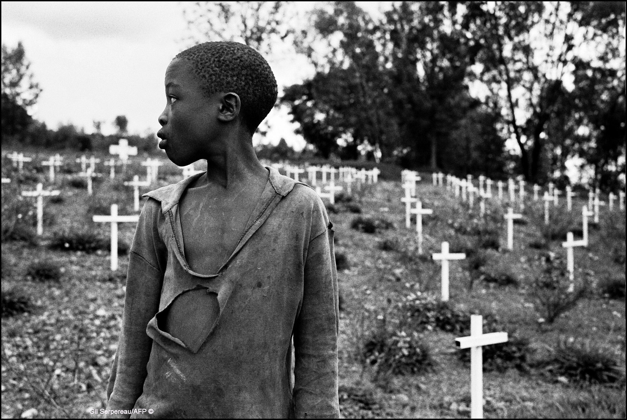 Foto in bianco e nero. Un bambino in un cimitero dove sono seppellite persone morte durante il genocidio in Ruanda.