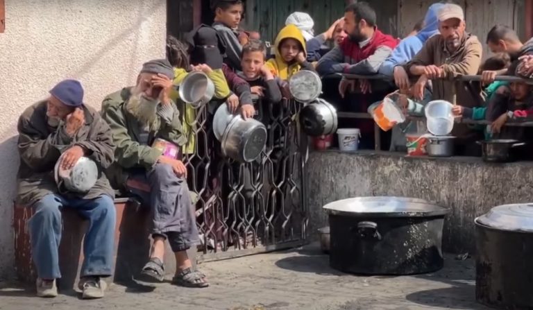 Persone a Gaza attendono cibo con le pentole in mano. La Corte internazionale di giustizia ha emesso ordinanze legalmente vincolanti che impongono a Israele di consentire la fornitura di aiuti umanitari e servizi di base. La Corte lo ha fatto due volte: la prima a gennaio e la seconda a marzo.