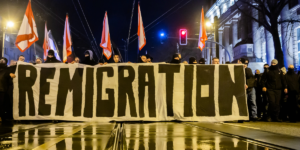 Manifestanti dietro uno striscione con la scritta Remigration
