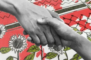 Due mani si stringono. Sullo sfondo una bandiera rossa con fiori e piante