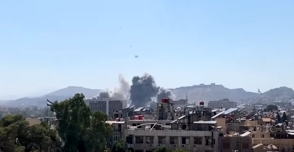 Immagini Reuters di una zona di Damasco sottoposta ad attacchi, si vedono edifici distrutti e una colonna di fumo che si leva dal centro