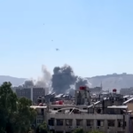 Immagini Reuters di una zona di Damasco sottoposta ad attacchi, si vedono edifici distrutti e una colonna di fumo che si leva dal centro