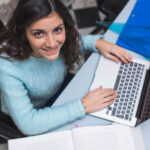 Una ragazza al computer si informa e guarda verso l'alto