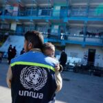Un membro dell'UNRWA assiste un bambino nella Striscia di Gaza bombardata da Israele