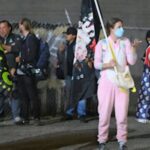 Tre persone travestite protesta con vestiti gonfiabili protestano contro le guardie di sicurezza di Trump. Tra loro uno vestito da pollo con la bandiera americana