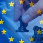 Una mano sposta una pedina degli scacchi sullo sfondo della bandiera europea