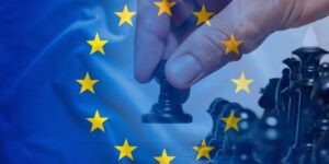 Una mano sposta una pedina degli scacchi sullo sfondo della bandiera europea