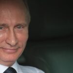 Il presidente della Russia Putin guarda sorridente da una finestra