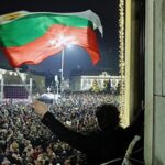 Le proteste in piazza in Bulgaria. Un manifestante con la bandiera bulgara