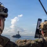 Soldati statunitensi in primo piano, sullo sfondo una imbarcazione venezuelana