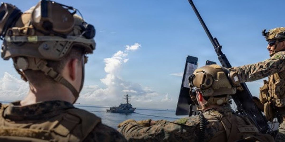 Soldati statunitensi in primo piano, sullo sfondo una imbarcazione venezuelana