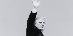 Foto in bianco e nero: al centro Trump che saluta con la mano destra alzata