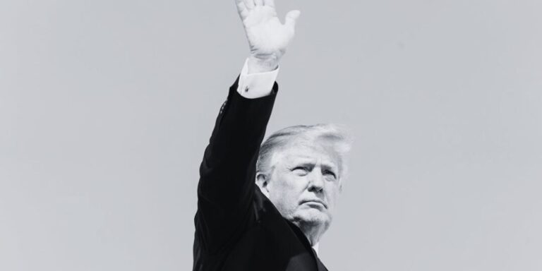 Foto in bianco e nero: al centro Trump che saluta con la mano destra alzata