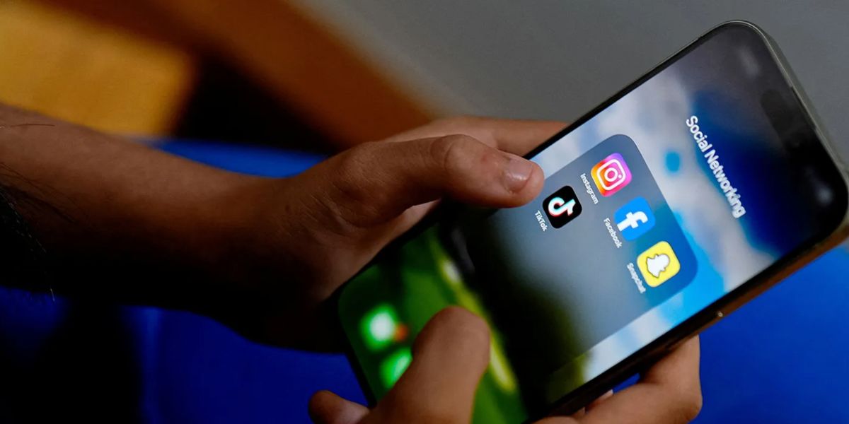 Un cellulare con le icone di Instagram, Facebook, TikTok e Snapchat tra le mani di un adolescente